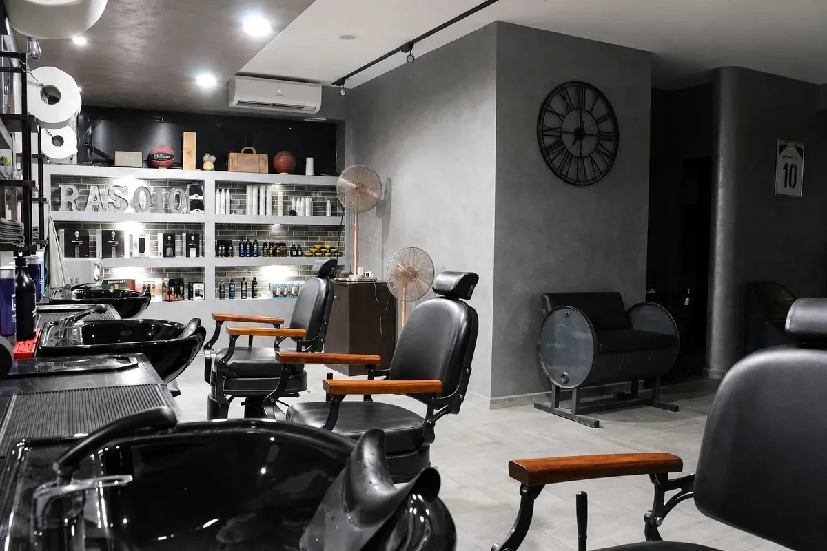 Rasoio Barberia: immagine degli interni con poltrone nere e finiture in legno tratta dal sito